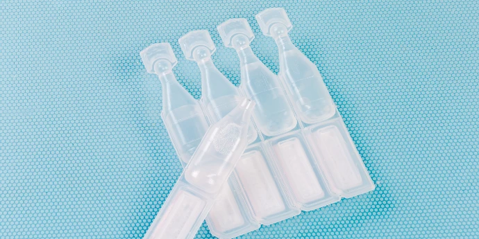Plastikowe, przezroczyste ampułki Plastikowe ampułki z bezbarwnym płynem, na niebieskim tle